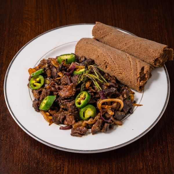 Ethiopian Gored Gored, a dish of cubed beef, onions, and jalapenos, served with injera.