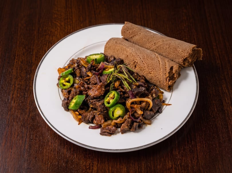 Ethiopian Gored Gored, a dish of cubed beef, onions, and jalapenos, served with injera.