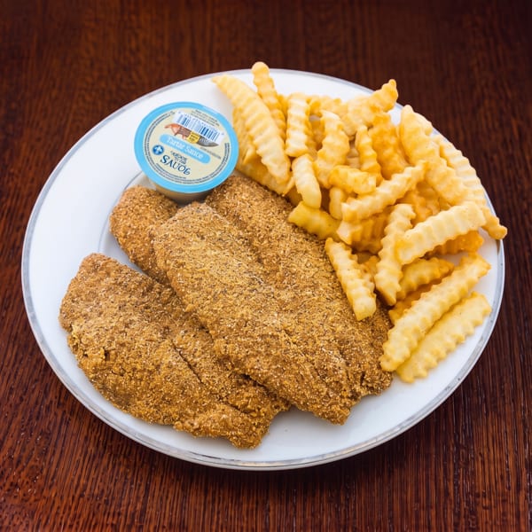 A white plate with three breaded fish fillets, crinkle-cut fries, and a cup of tartar sauce.