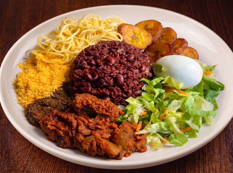A large plate of food with rice and beans, spaghetti, plantains, salad, and meat.